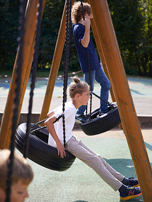 Boys swinging on a wooden swing frame.